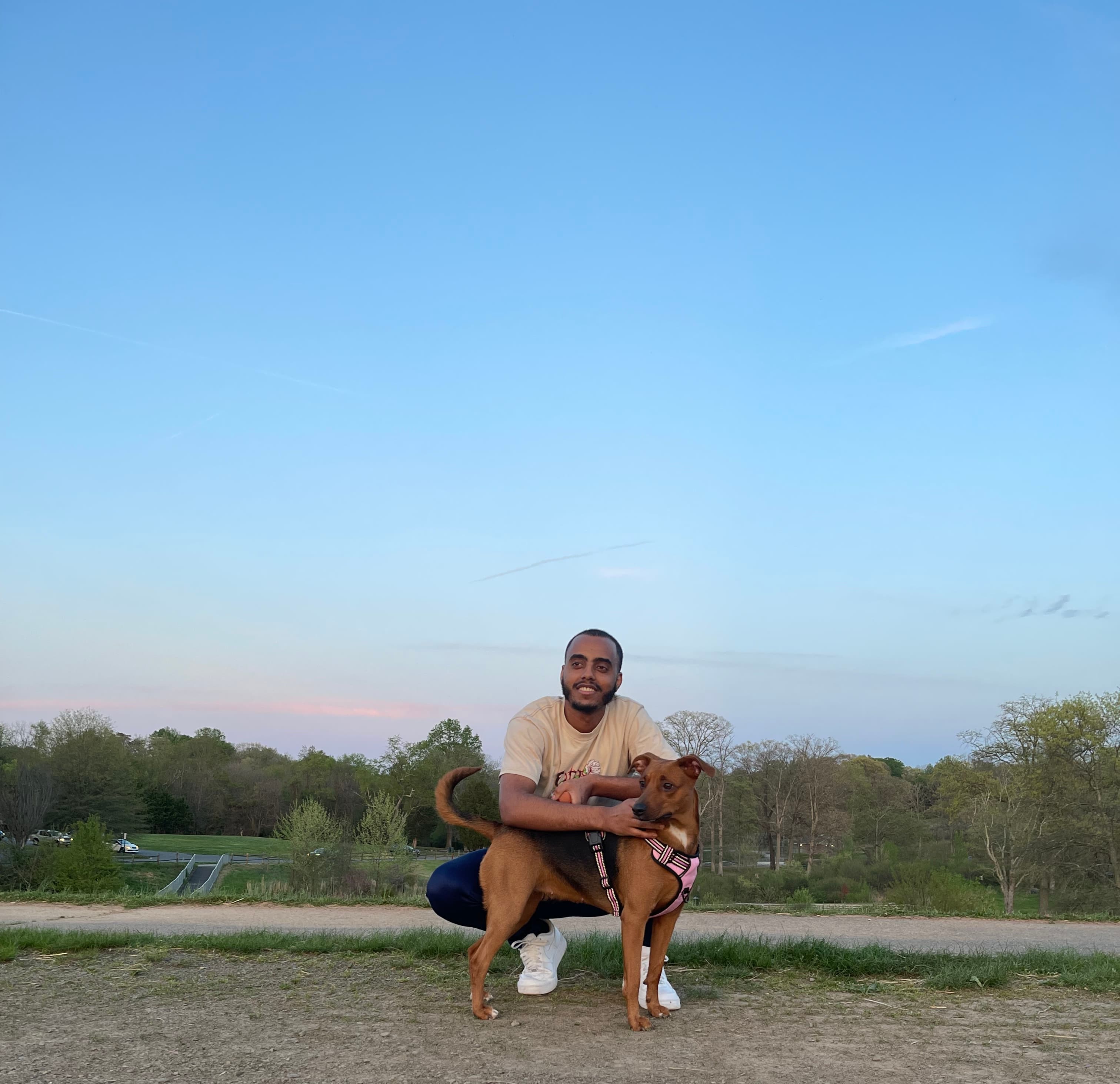 Teferi Blaze Tesfaye of Bark & Blaze kneeling outdoors with a dog